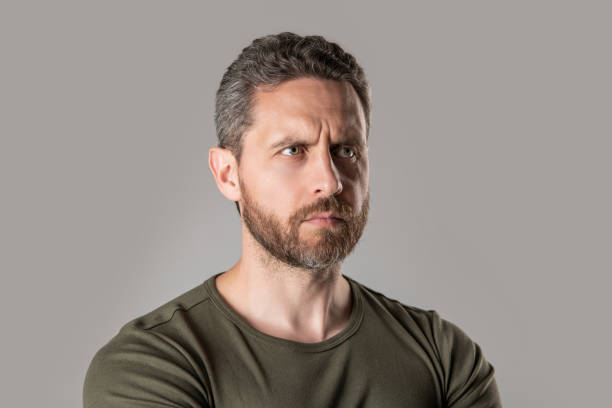 handsome caucasian man isolated on grey background. caucasian man in studio. photo of caucasian man with stubble. caucasian man with stubble wear tshirt.