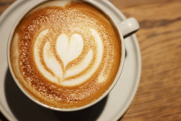 istock Creamy cappuccino with beautiful flower heart pattern in a white ceramic cup on a wooden table in a coffee shop. Closeup. Copy space. Top view 2182698992
