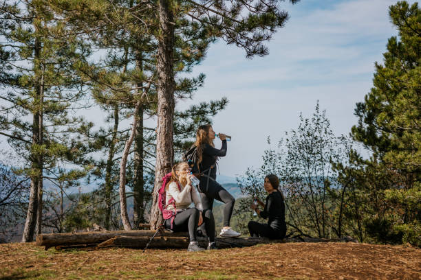 istock Three friends enjoying a hike while taking a break with water bottles in a serene forest setting on a sunny day 2182699005