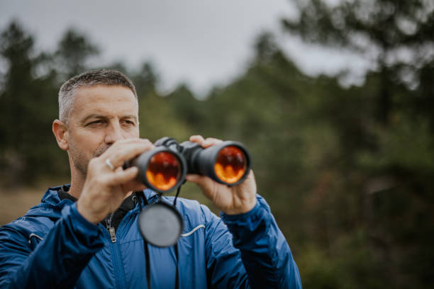 istock A man looks through binoculars while exploring nature during a cloudy day in the forest 2182699838
