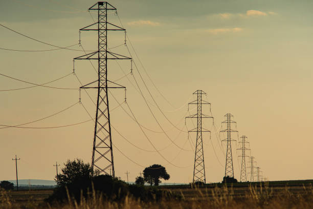 istock High voltage poles standing in the field 2182700244