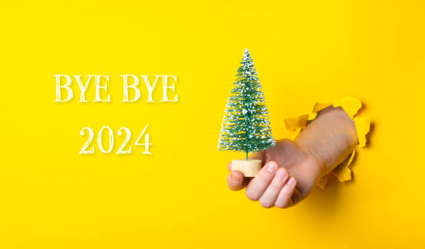 istock Hand holding a small Christmas tree in front of a yellow background 2182702884