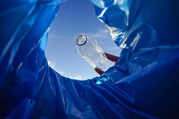 African man holding a cardboard box full of plastic bottles for recycling. Environmental awareness.