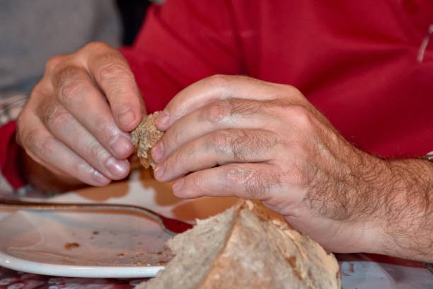 Close-up of a man's hands holding a piece of rustic bread. Perfect for themes of tradition, food, simplicity, and artisanal craftsmanship