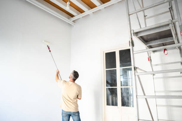 istock Painter using telescopic paint roller painting white wall in apartment 2182706271