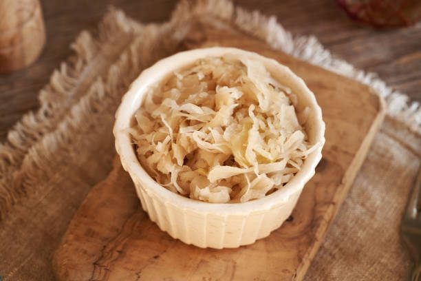 Homemade fermented cabbage or sauerkraut in a white bowl on a wooden table