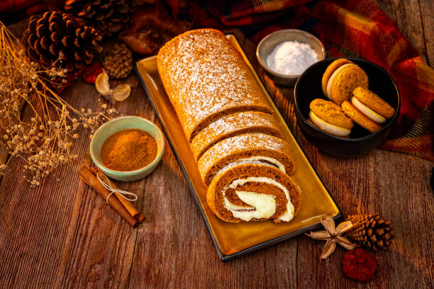 Pumpkin Spice Cheesecake Roll surrounded by sweet pastries on a Retro wood Background
