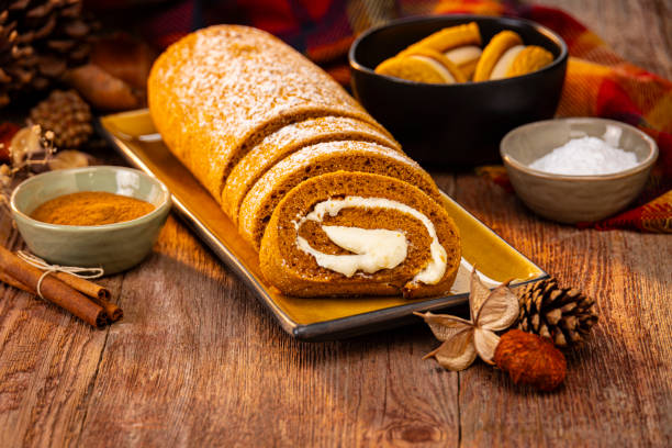 Pumpkin Spice Cheesecake Roll surrounded by sweet pastries on a Retro wood Background