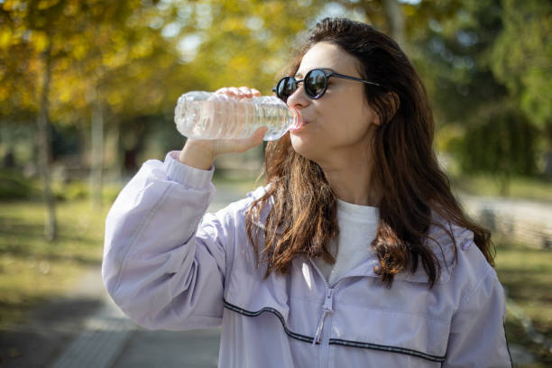 istock Woman taking a walk in the park drinks water 2182716476