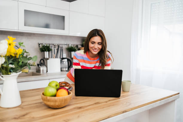 istock A young woman uses a mobile phone reading the latest news while preparing for breakfast 2182718549