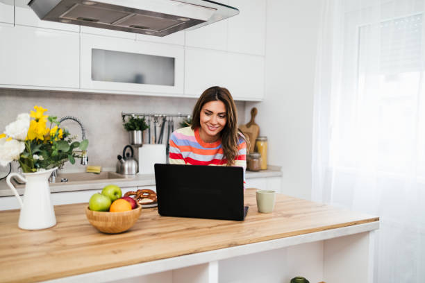 istock A young woman uses a mobile phone reading the latest news while preparing for breakfast 2182718558