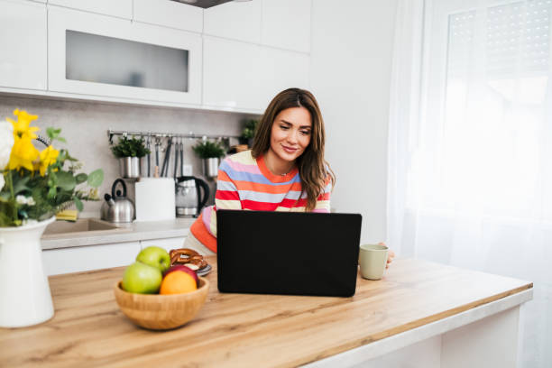 istock A young woman uses a mobile phone reading the latest news while preparing for breakfast 2182718596