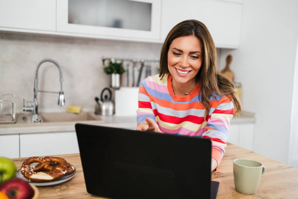 istock A young woman uses a mobile phone reading the latest news while preparing for breakfast 2182718742