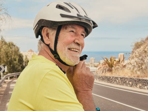 istock Cheerful smiling active bearded senior man adjusting his cyclist helmet before riding bicycle on the street. Elderly male enjoying healthy lifestyle and retirement or vacation 2182719384