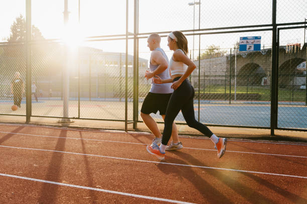 istock Side view of two young people running on an athlete track. 2182719546
