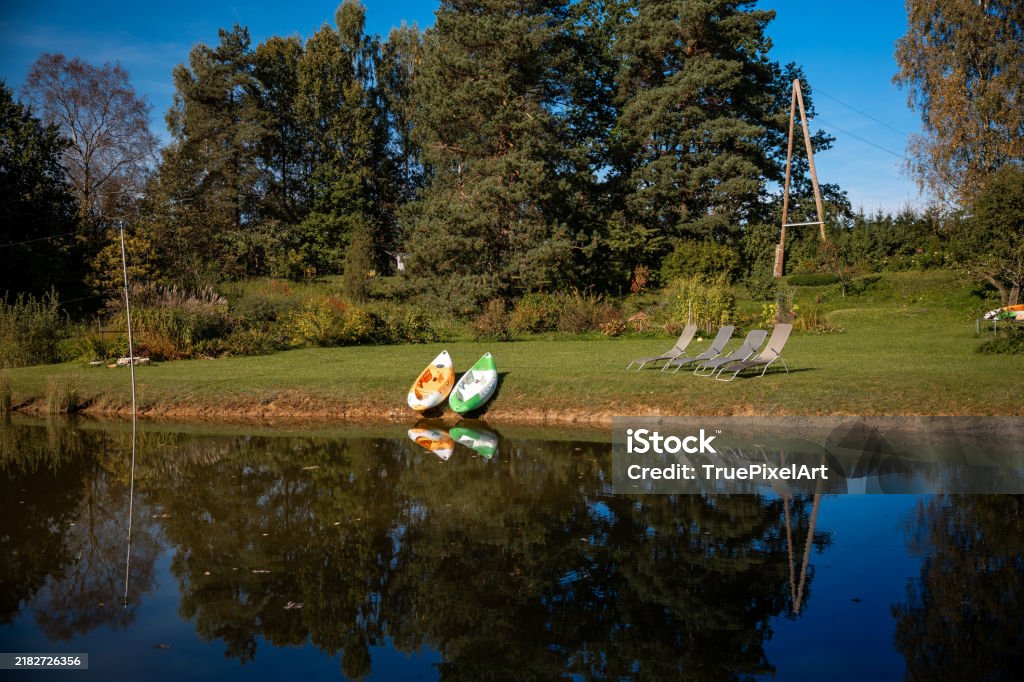 Poklidná scenérie na břehu jezera s kajaky a lehátky na travnatém břehu - Bez autorských poplatků Aktivita Stock fotka Poklidná scenérie na břehu jezera s kajaky a lehátky na travnatém břehu - Bez autorských poplatků Aktivita Stock fotka