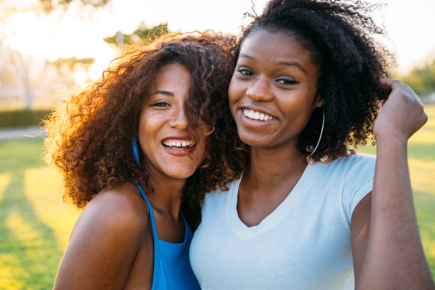 istock Two friends smiling and having fun outdoors in a park 2182733384