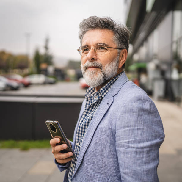 istock senior concentrated man use mobile phone in front modern company 2182733964