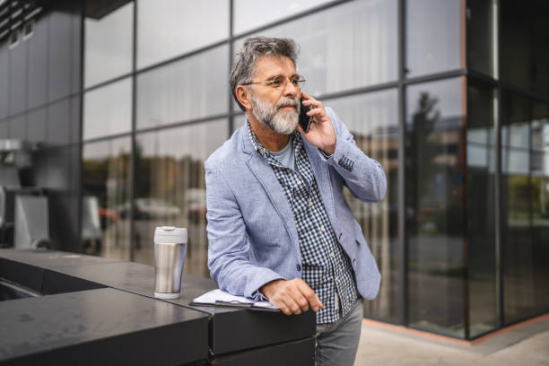 istock senior man talk on mobile phone and use clipboard 2182734621