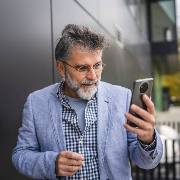 istock senior concentrated man use mobile phone in front black background 2182737675