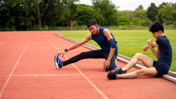 istock Two young men stretching and cooling down on outdoor running track after workout session with copy space 2182740303