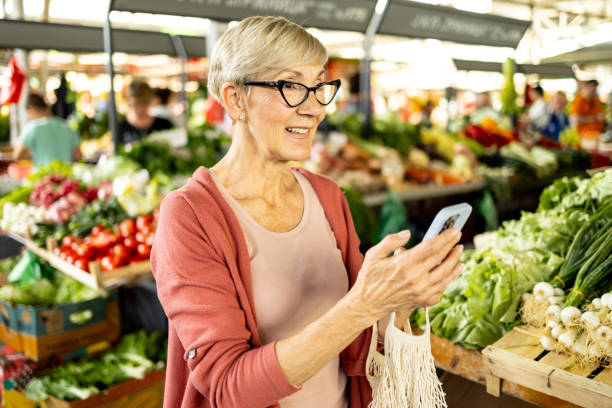 istock Woman at market using smartphone to check list 2182742816