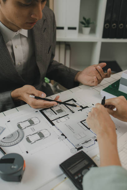 istock engineers are sitting discussing a construction plan that needs to be revised to make the structure stronger, an architect and assistant are brainstorming and examining the blueprints 2182755037