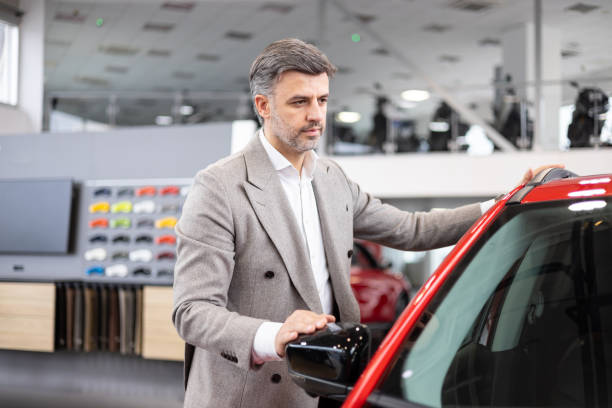 istock Man inspecting a red car at a dealership 2182757464