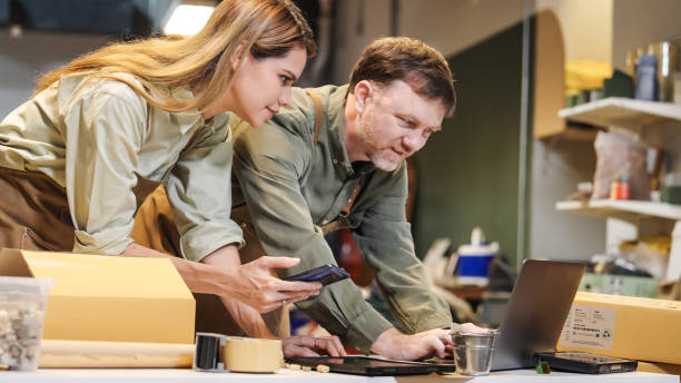 istock Two small business warehouse worker wearing green apron checking reviewing inventory working with  computer while examining products with gardening and art craft Sustainability friendly zero waster and plastic free  quality control 2182765304
