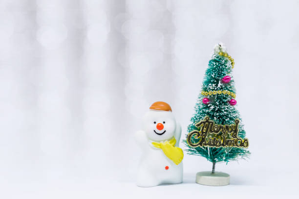 istock Cute little snow man with Christmas tree over blurred white bokeh background 2182768983