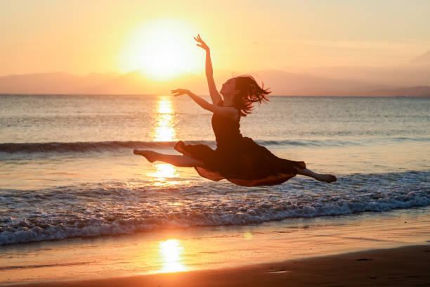 istock Beautiful young lady jumping in sunset beach 2182774790