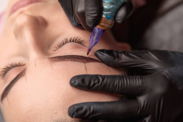 istock Beautician applying permanent makeup on eyebrows of client 2182775945