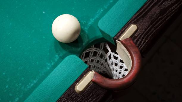 istock Playing Russian billiards on a green table. A white ball rolls and hits another which pockets into the middle pocket. A successful shot close up. Pastime at home playing sport game hobby 2182776846
