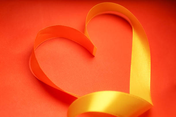 Heart shape yellow ribbon on red background
