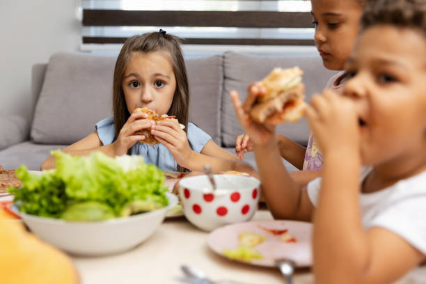 istock Three children enjoying sandwiches with fresh veggies. 2182783483