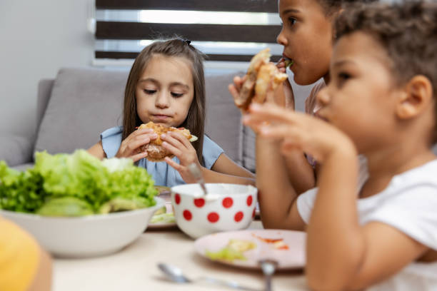 istock Three children enjoying a meal together at a table. 2182783511