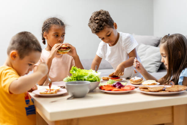 istock Children enjoying lunch around a table with salads. 2182784380