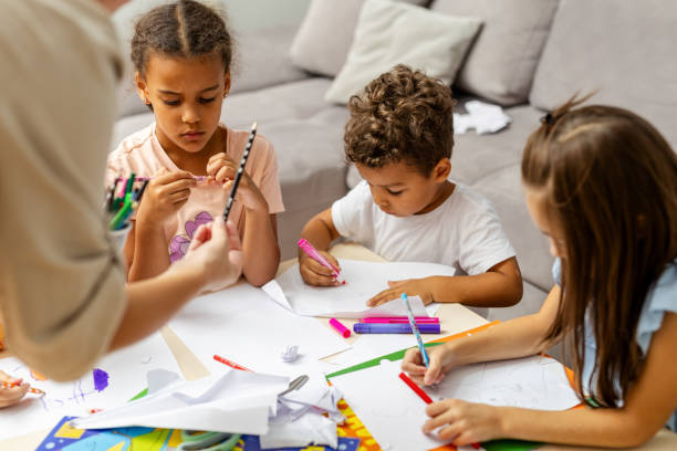 istock Children drawing together at a table with helpers nearby. 2182785694