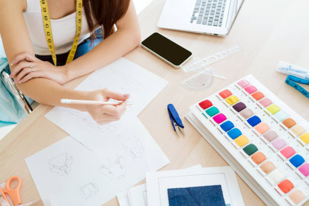 istock A creative workspace featuring a person sketching with watercolor supplies, a laptop, and various art tools scattered on a desk. 2182790765