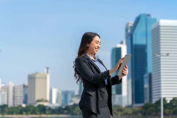 istock Asian Businesswoman Using Digital Tablet in Modern Urban Setting with Skyline Background 2182790979