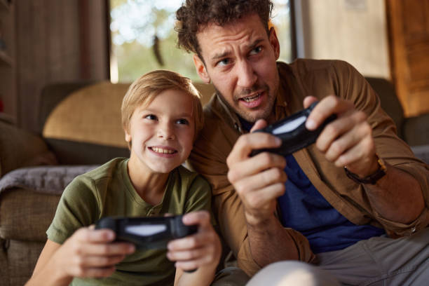 istock Carefree father and son having fun while playing video games at home. 2182792904