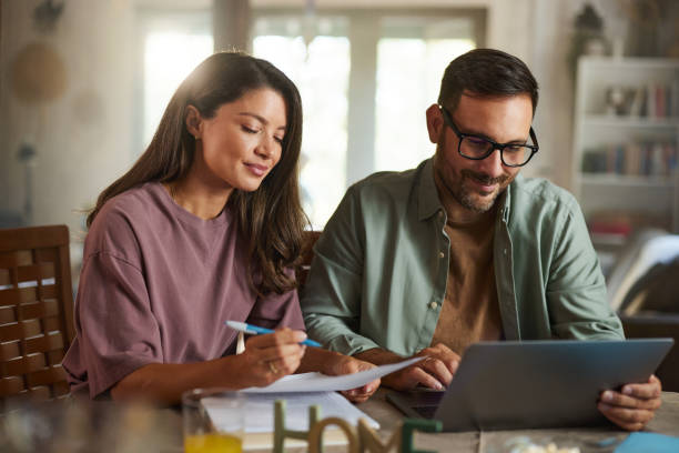 istock Smiling couple working on reports and laptop at home. 2182793587