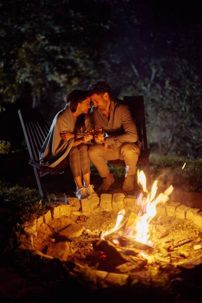 istock Affectionate couple toasting by the campfire at night. 2182793908