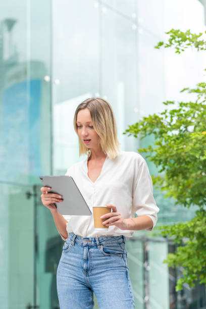 istock White Woman Using Tablet and Holding a Coffee Cup in Urban Environment 2182794437