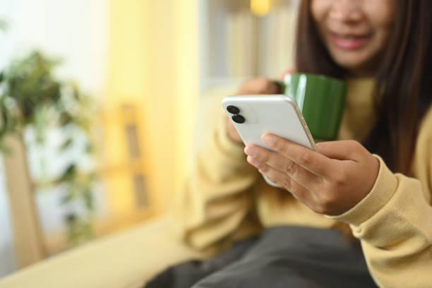 istock Smiling young woman enjoying a warm drink while checking messages on her mobile phone 2182794954