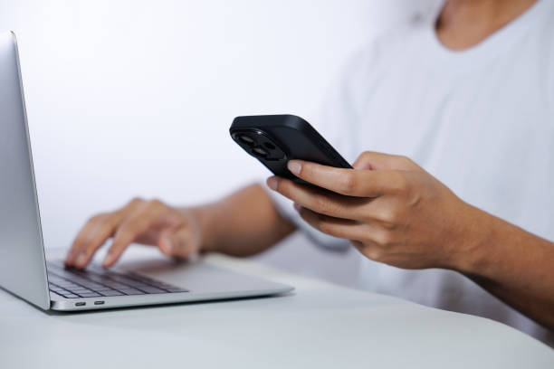 istock Middle-aged man in white shirt using laptop and smartphone on white background. 2182796388