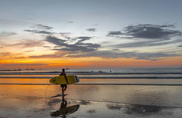 istock Surfer at sunset beach with vibrant sky. 2182798003