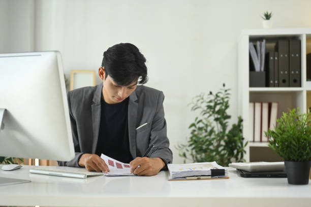 istock A man in a suit is sitting at a desk with a computer monitor and a notebook 2182799605