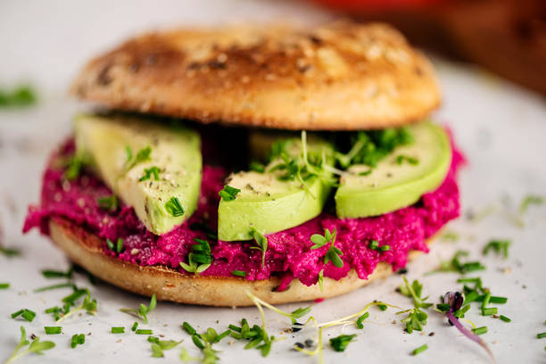 This vegan bagel is loaded with delicious beetroot-flavoured hummus and avocado and a slice of a beefsteak tomato seasoned with salt, pepper and micro greens.