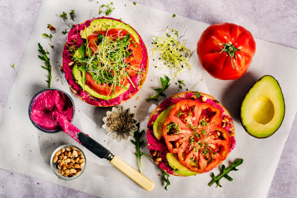 These vegan bagels are loaded with delicious beetroot-flavoured hummus and avocado and a slice of a beefsteak tomato seasoned with salt, pepper and micro greens.